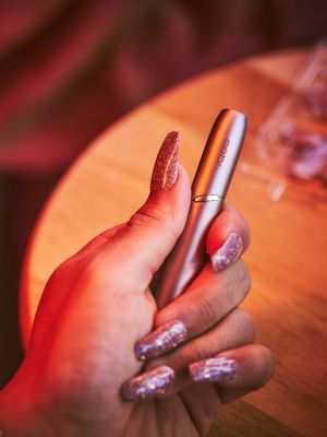 Une personne avec de longs ongles qui porte un appareil IQOS