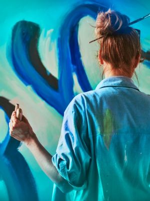 An artist painting while holding an IQOS device.