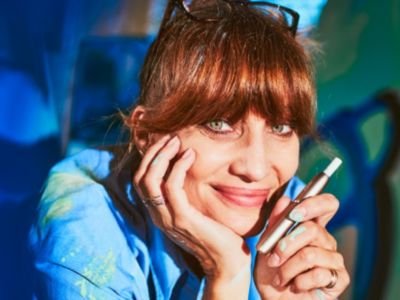 A woman resting her head in her hand while holding an IQOS device. 