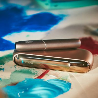 An artist painting while holding an IQOS device.