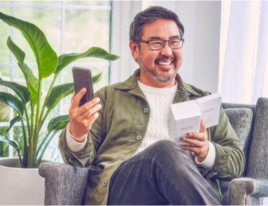 A smiling man holdiing an IQOS device.