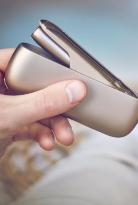 Un homme qui tient un appareil IQOS