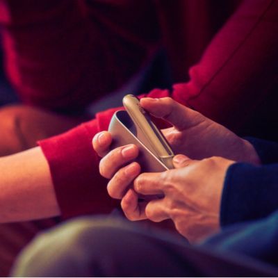 Una mujer de amarillo con un dispositivo IQOS. 