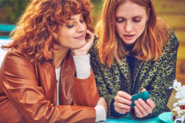 A gold IQOS device in its holder in a person's hand.