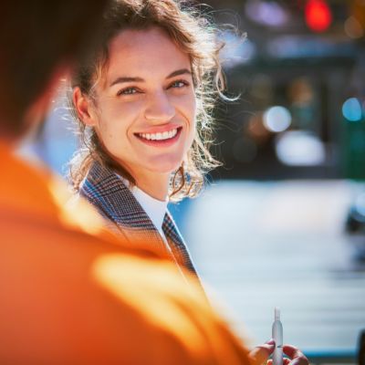 A smiling woman in a street scene.
