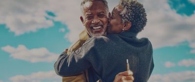 A man holding an IQOS device embraces his partner.