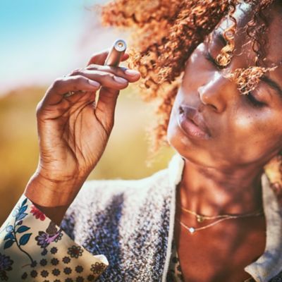 Una mujer con el pelo rizado sostiene un dispositivo IQOS.