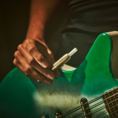 A guitarist holding an IQOS device.