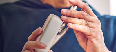 Close up of a person holding an IQOS device.