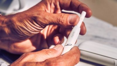 A person placing a HEETS stick into an IQOS device.