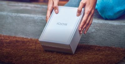 A woman holding an IQOS box. 