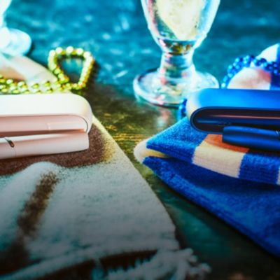 Stylets et chargeurs de poche IQOS 3 DUO bleu et blanc posés sur une table 