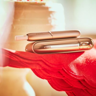 Brilliant gold IQOS 3 DUO holder with HEETS stick on charger on red fabric