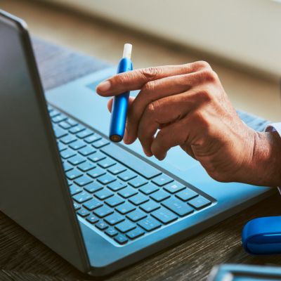 Stellar blue IQOS 3 DUO holder and charger in a businessman's hand