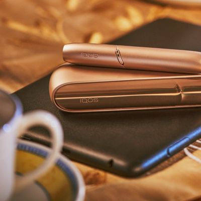 Brilliant gold IQOS 3 DUO on top of charger