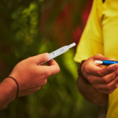 Close up of a white IQOS holder with HEETS stick in a person's hand