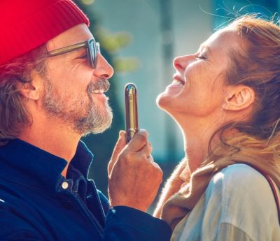 Happy couple embracing as he holds an IQOS 3 DUO charger between them