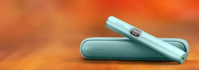 Kit Iqos Iluma i couleur Aigue-Marine posé sur une table dans le logo IQOS