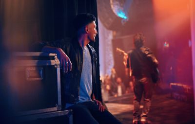 Hombre sentado viendo a alguien toca guitarra