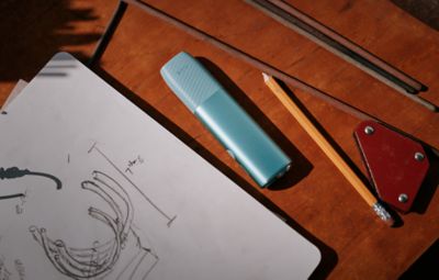 IQOS Iluma i turquesa con cargador pastel en vista lateral sobre fondo blanco