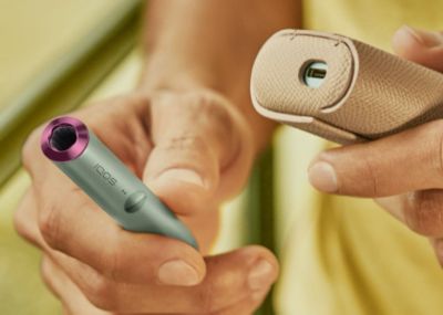 An IQOS ILUMA PRIME Holder and Pocket Charger in a person's hands.