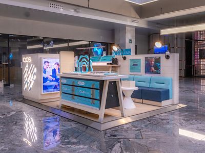 Exhibición IQOS ILUMA en centro comercial con estructura iluminada y mesa de demostración.