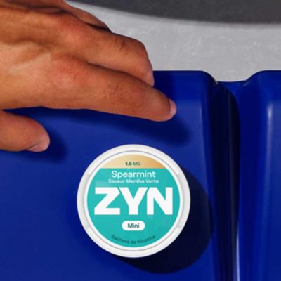 Boîte de sachets de nicotine ZYN Spearmint 1.5MG posée sur un fond bleu