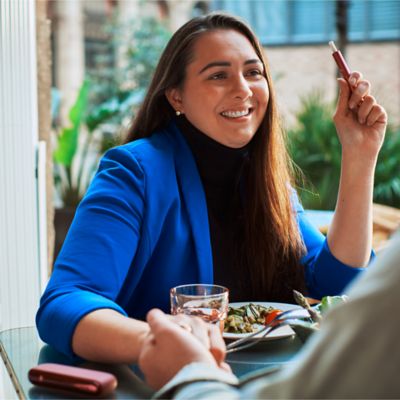 Woman using IQOS device at dinner table