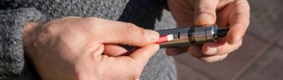 Muž doplňujúci e-cigaretu