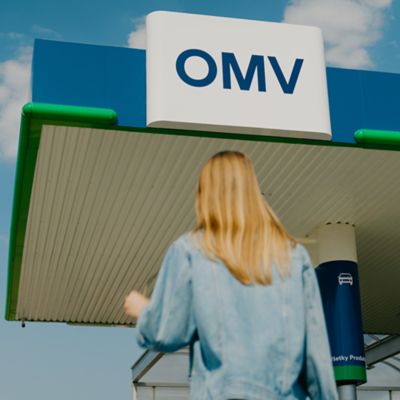 Žena vchádzajúca na čerpaciu stanicu OMV.
