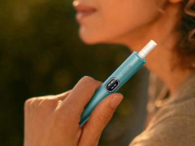 Ruka vyťahujúca ohrievacie zariadenie IQOS z nabíjačky.