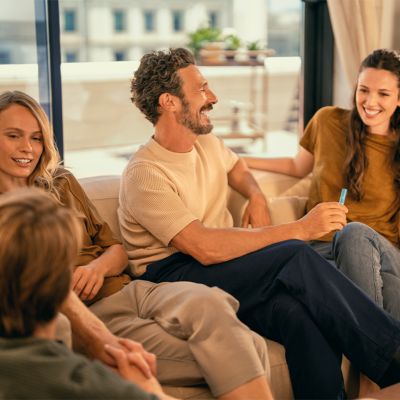 Ľudia sa rozprávajú na sedačke, muž drží IQOS zariadenia