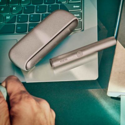 Brilliant gold IQOS 3 DUO holder with HEETS stick on charger on red fabric