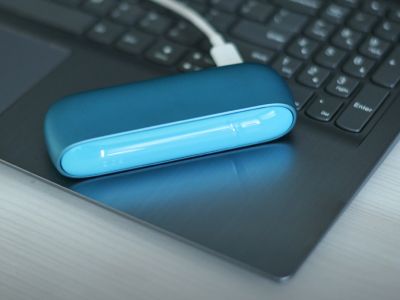 Ein blaues IQOS ORIGINALS DUO Gerät wird über ein USB-Kabel an einen Laptop angeschlossen.