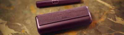IQOS Iluma i Prime morado y verde sobre superficie de mármol.