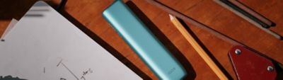 IQOS Iluma i ONE turquesa colocado sobre mesa junto a herramientas de diseño