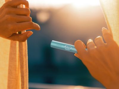 Close-up of hands holding an IQOS device.