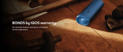 Blue BONDS 2 by IQOS device on a wooden floor beside a tool and a metal gear piece