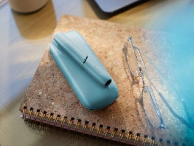 A person holding a blue IQOS device.