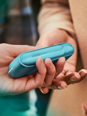 A person with long finger nails. Holding an IQOS device.