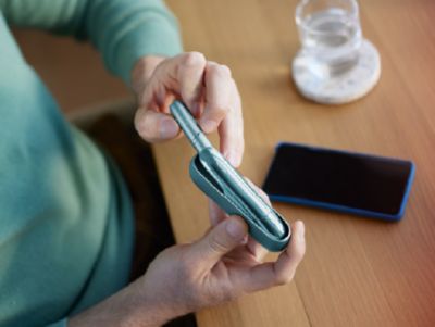 A woman resting her head in her hand while holding an IQOS device. 