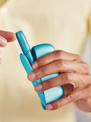 An artist painting while holding an IQOS device.