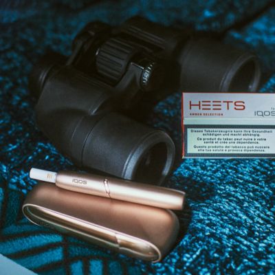 Gold IQOS 3 DUO kit next to a pair of binoculars