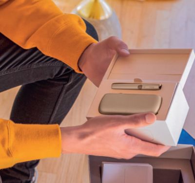 A smiling man holdiing an IQOS device.