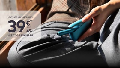 Frau entnimmt Holder aus IQOS ORIGINALS DUO Pocket Charger in der Farbe Turquoise.