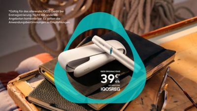 Ein silbernes IQOS ORIGINALS DUO platziert auf einem Stapel Notizbücher.