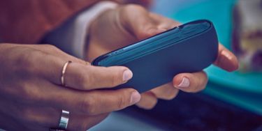 Woman holding her grey IQOS - IQOS charging slowly