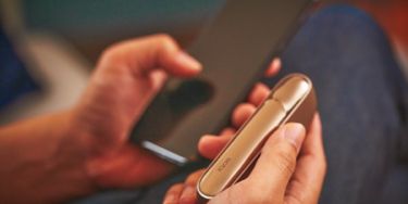 Man with a gold IQOS Duo and a mobile in his hands