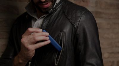 A close-up of a man tucking his IQOS 3 MULTI into his black leather jacket