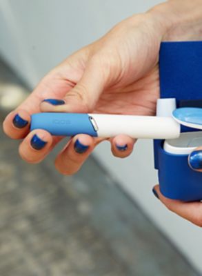 A mobile and a gold IQOS kit on a table